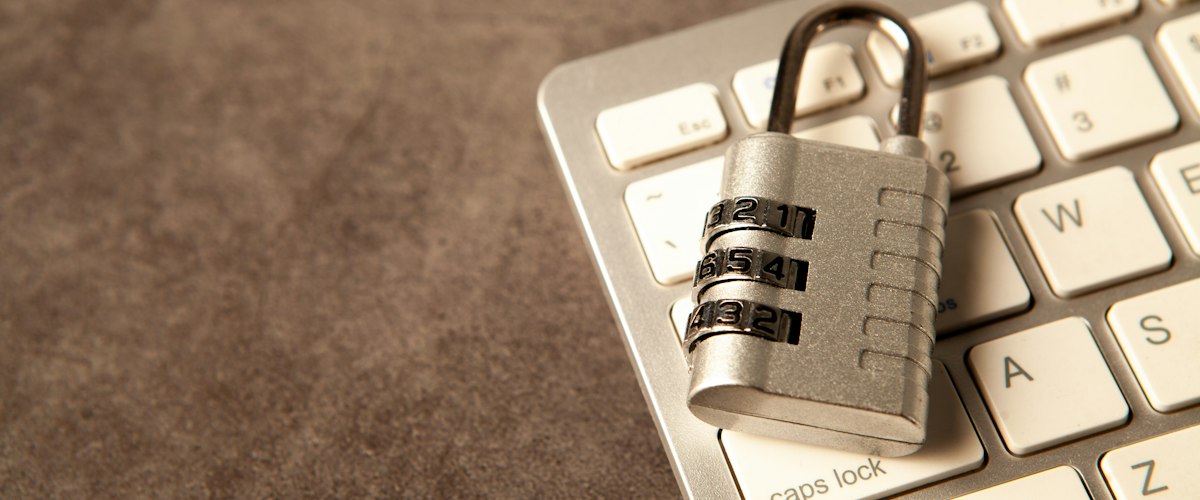 A silver combination padlock resting on a laptop keyboard